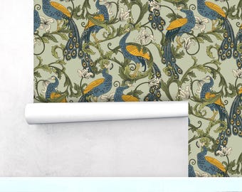 Puede incluir: Rollo de papel pintado con un patrón repetido de pavos reales azules con detalles amarillos, sobre un fondo verde claro. El diseño incluye flores blancas y follaje verde, creando una estética vintage. El rollo está parcialmente desenrollado.