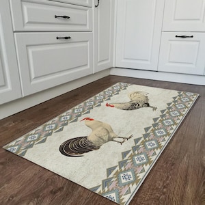 May include: A white kitchen rug with a geometric pattern in shades of blue, pink, and brown. Two roosters are featured on the rug, one in a standing position and the other in a walking position.