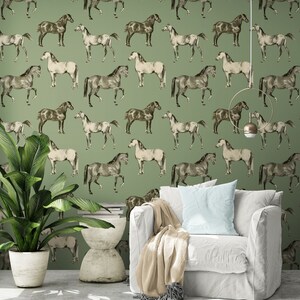 May include: A green wallpaper with a repeating pattern of white and brown horses. The wallpaper is in a living room with a white armchair and a green plant in a white pot.