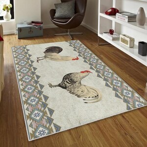 May include: A white and gray area rug with a geometric pattern in shades of pink, blue, and brown. The rug features a stylized illustration of two roosters with red combs.