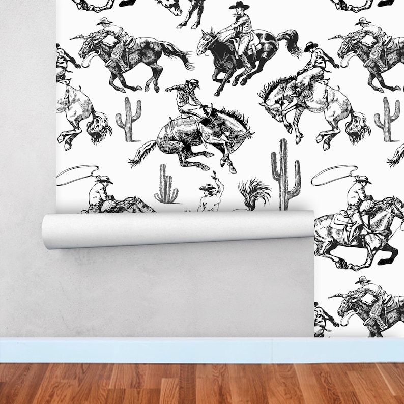 May include: Black and white illustration of cowboys riding horses and lassoing. The pattern repeats with cacti and lasso ropes.