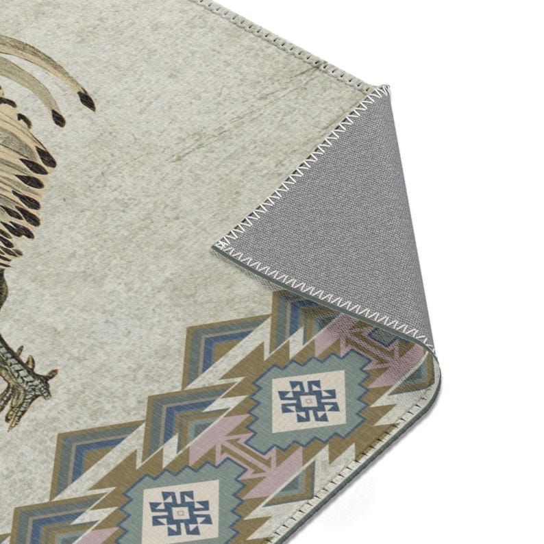 May include: A beige rug with a geometric pattern in shades of blue, green, and pink. The rug features a stylized bird design in the upper left corner. The rug has a gray backing with a stitched edge.