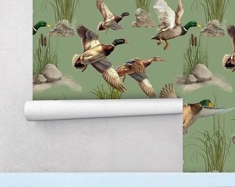 May include: Wallpaper roll featuring a repeating pattern of flying ducks, rocks, and reeds on a muted green background. The ducks have brown, white, and green feathers. The wallpaper is partially unrolled, revealing a white backing.