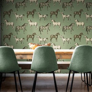 May include: A dining room with a green wallpaper featuring a repeating pattern of horses. The wallpaper has a vintage feel. There are three chairs with green upholstery and black metal legs. The chairs are arranged around a wooden table.