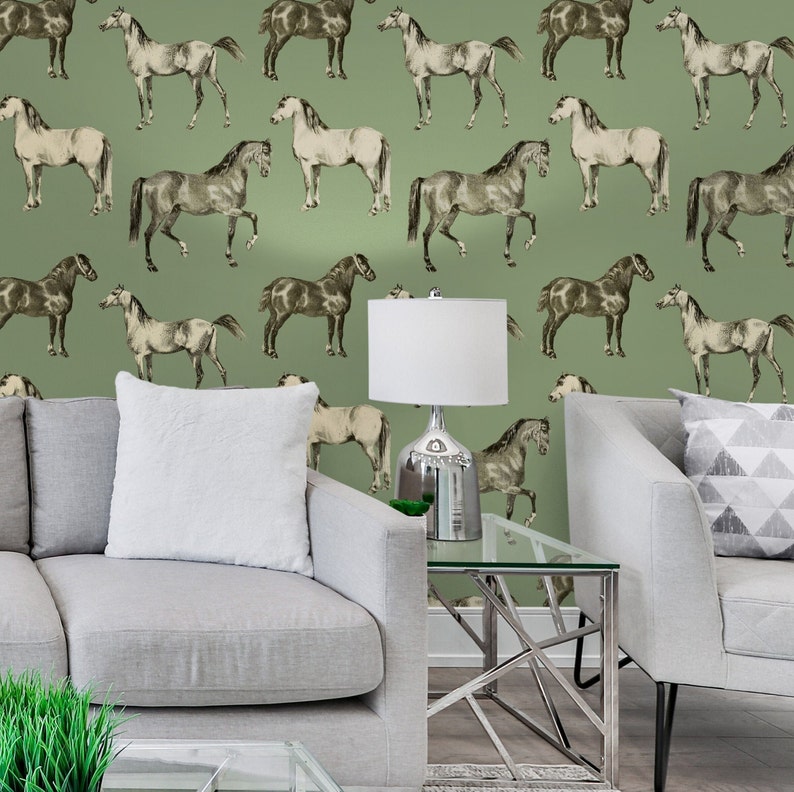 May include: A living room interior with a green wallpaper featuring a repeating pattern of black and white horses. The room has two gray sofas, a glass coffee table, and a lamp with a white lampshade.