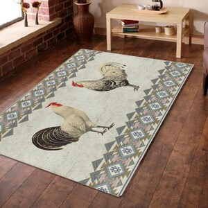 May include: A white and beige rug with a geometric pattern in shades of brown, blue, and pink. Two roosters are featured on the rug, one white and one brown, with red combs.