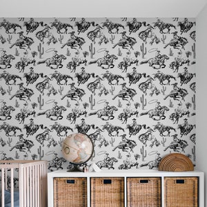 May include: Black and white wallpaper featuring a repeating pattern of cowboys riding horses. The cowboys are wearing hats and holding ropes. The horses are in various poses, some are jumping and some are running. The wallpaper is on a white wall in a room with a crib and a globe.