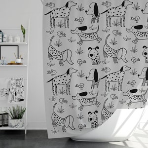 May include: A light gray shower curtain featuring a repeating pattern of black and white cartoon dogs, birds, and leaves. The dogs have various poses and markings, including spots and solid black ears. The curtain is hanging in front of a white bathtub.