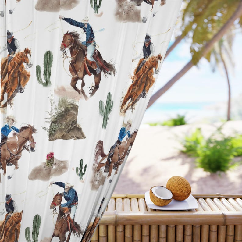 May include: White curtain panel featuring a watercolor design of cowboys riding horses, cacti, and desert landscapes. The cowboys are depicted in action, with a blue and brown color scheme. The curtain is partially covering a tropical outdoor scene.