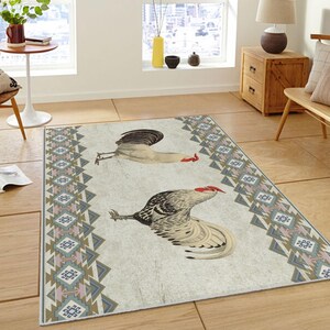May include: A white and gray area rug with a geometric pattern in shades of blue, pink, and brown. Two roosters are depicted on the rug, one white and one gray.