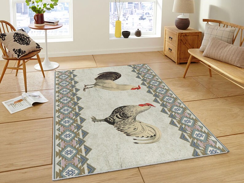 May include: A white and gray area rug with a geometric pattern in shades of blue, pink, and brown. Two roosters are depicted on the rug, one white and one gray.
