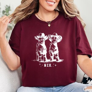 a woman sitting on a couch wearing a t - shirt with two dogs on it