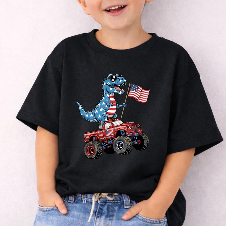 A young boy wearing a black t-shirt with a graphic of a dinosaur riding a red truck with American flag-like flags on it.