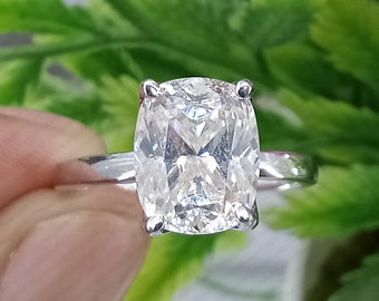May include: A silver ring with a large, clear, cushion-cut diamond.