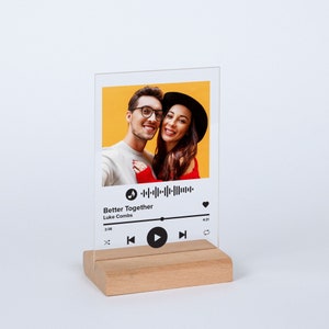 May include: A clear acrylic photo display featuring a couple's photo against a yellow background. The design includes a music player interface with the song title "Better Together" by Luke Combs. The display is mounted on a rectangular wooden base.