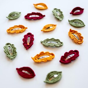 May include: Assortment of crocheted leaf-shaped hair clips in green, red, and yellow.