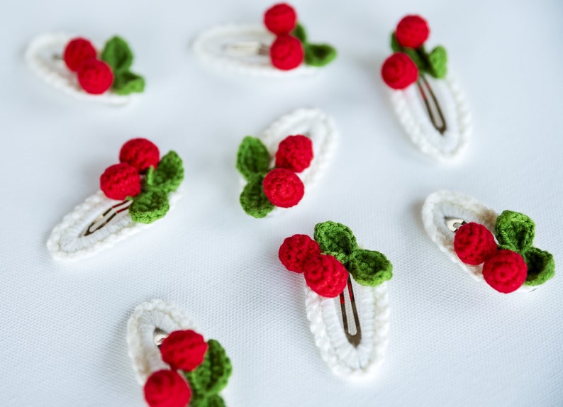 Puede incluir: Conjunto de siete pinzas para el pelo de crochet blanco con bayas de crochet rojo y verde.