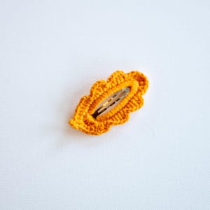 May include: A crocheted orange leaf-shaped hair clip with a metal clasp.