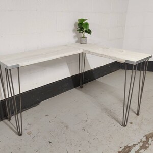 K&ouml;nnte beinhalten: Wei&szlig;er Ecktisch mit Haarnadelbeinen. Der Tisch ist aus recyceltem Holz und hat einen rustikalen Look.