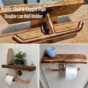 May include: Rustic wooden shelf with a copper pipe double toilet roll holder. The shelf is mounted to the wall and has a copper pipe that extends out from the shelf to hold two rolls of toilet paper.