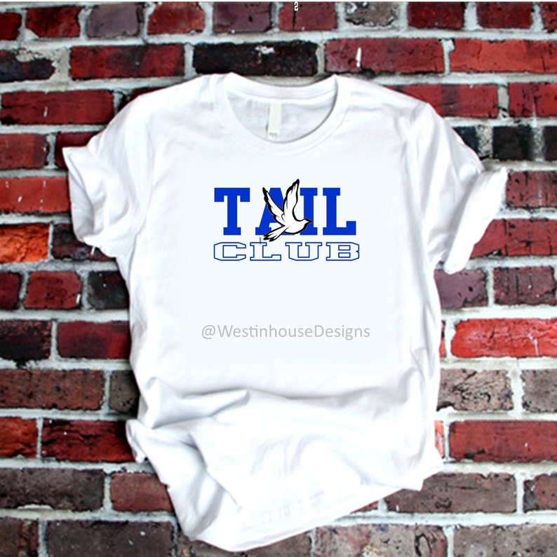 May include: White t-shirt with a blue and white graphic that says "TAIL CLUB" with a white dove flying above the word "TAIL". The text "@WestinhouseDesigns" is below the graphic.