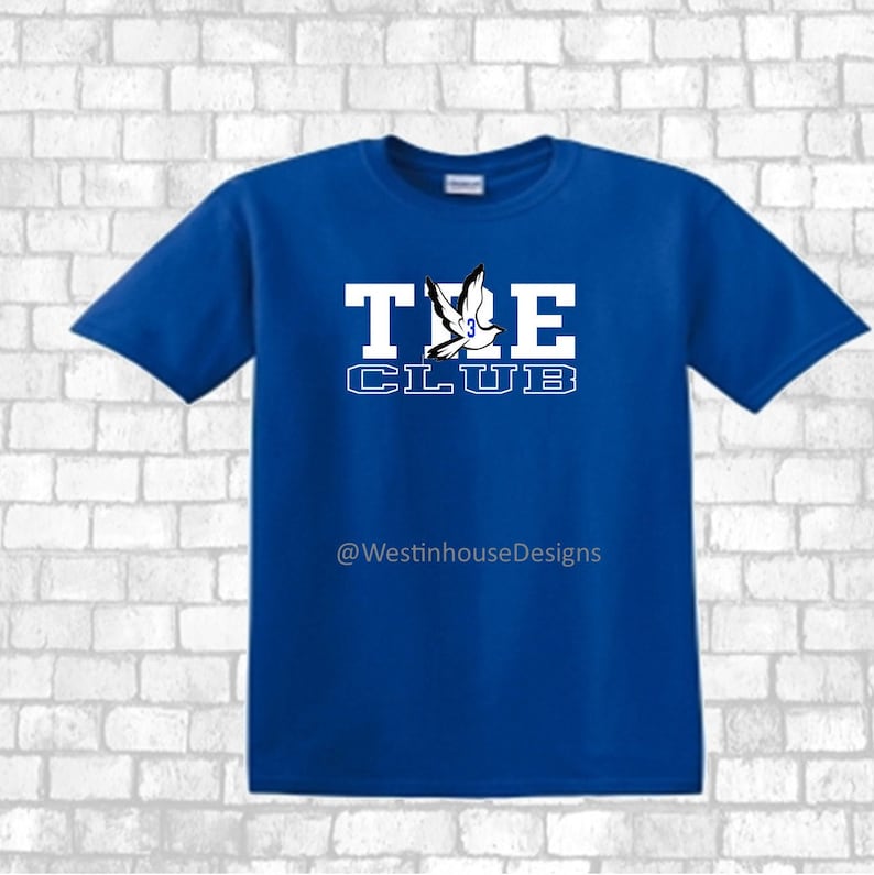 May include: A royal blue t-shirt with a white dove graphic and the text "THE CLUB" in white block letters. The text "@WestinhouseDesigns" is printed in black below the graphic.