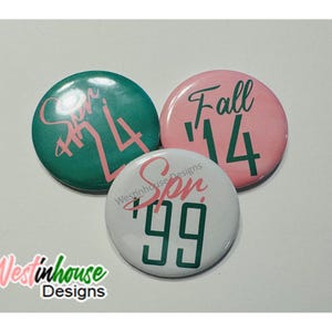Op de afbeelding: Drie ronde knoppen met verschillende gekleurde achtergronden en witte tekst. De eerste knop is groen met roze tekst die "Sum '24" zegt. De tweede knop is roze met groene tekst die "Fall '14" zegt. De derde knop is wit met groene tekst die "Spr '99" zegt.