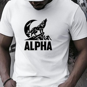 May include: White t-shirt featuring a black wolf howling at the moon graphic, with the word "ALPHA" underneath. The person is wearing a white baseball cap and black jeans.