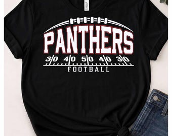 Può includere: Una t-shirt nera a maniche corte con una grafica bianca e rossa di un pallone da football, il testo PANTHERS sopra un design di un campo da football con linee di yard e la parola FOOTBALL in lettere maiuscole bianche sotto il campo.