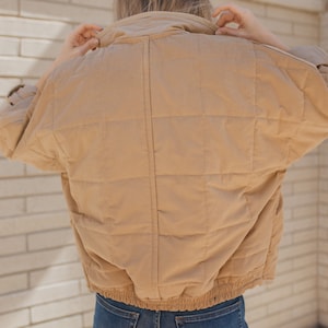 May include: A tan quilted jacket with a zipper closure and a drawstring waist.