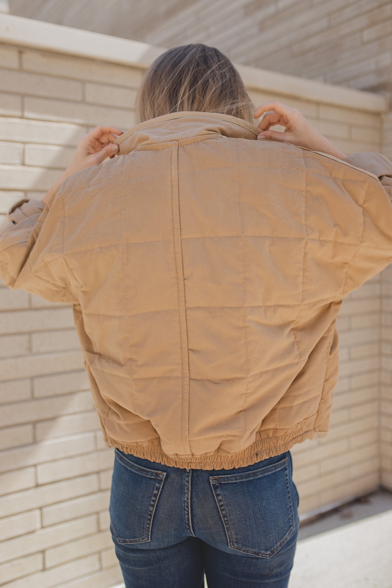 May include: A tan quilted jacket with a zipper closure and a drawstring waist.