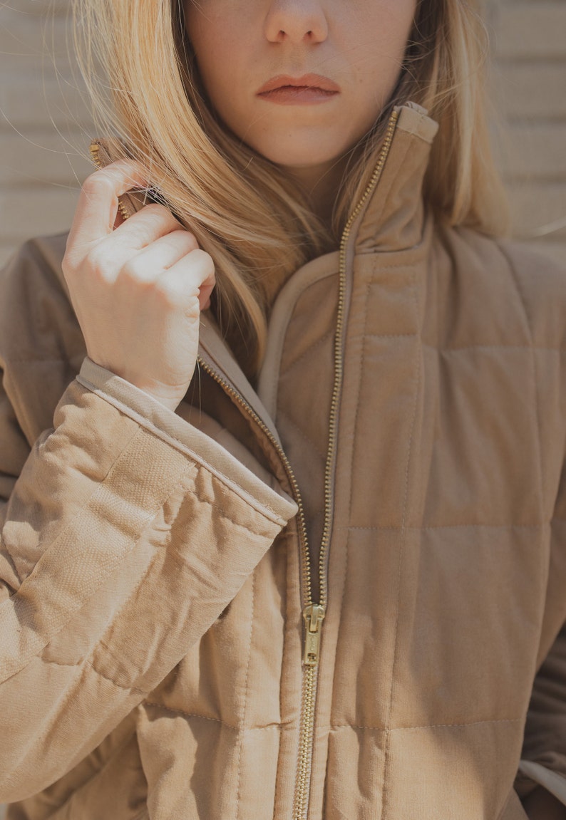 May include: A brown quilted jacket with a zipper closure. The jacket has a high collar and a relaxed fit.