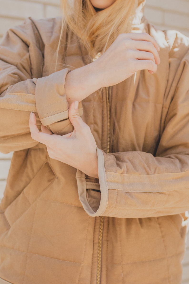 May include: A brown quilted jacket with a zipper closure and a light brown trim around the edges. The jacket is made of a soft, comfortable material.