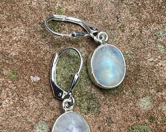May include: A pair of silver dangle earrings with oval-shaped moonstone gemstones. The earrings have a leverback closure.