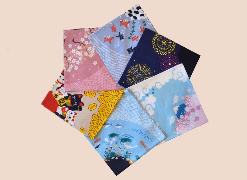 May include: Six fabric squares with different Japanese-inspired designs. The squares are arranged in a star shape. The designs include cherry blossoms, fish, clouds, fireworks, and lucky cats.