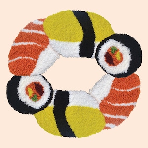 May include: A close-up of a sushi-themed rug made of yarn. The rug is shaped like a circle and features different types of sushi, including nigiri, maki, and sashimi. The rug is made with a variety of colors, including red, orange, yellow, black, and white.
