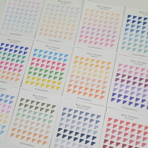 May include: Ten sheets of mini corner stickers with different color gradients. Each sheet has 49 triangle stickers. The color gradients include pastel blue, peach, pink, blue, green, yellow, orange, purple, gray, and red.