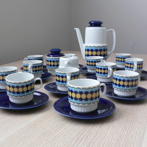 May include: A vintage tea set with a blue and yellow geometric pattern. The set includes a teapot, sugar bowl, creamer, and 10 cups and saucers.