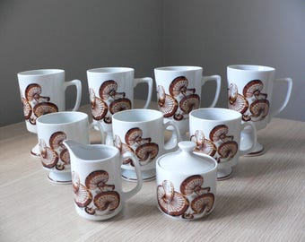 Set da caffè in ceramica a tema funghi: tazze con piedistallo, zuccheriera e lattiera.