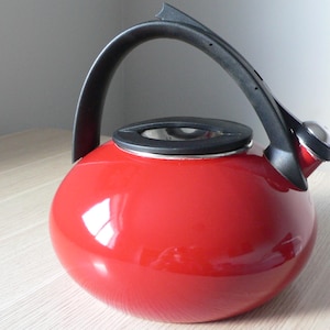 Bouilloire sifflante en émail rouge COPCO en acier inoxydable avec poignée noire. Bouilloire vintage avec plaque de cuisson, design moderne, combinaison rouge et noir.