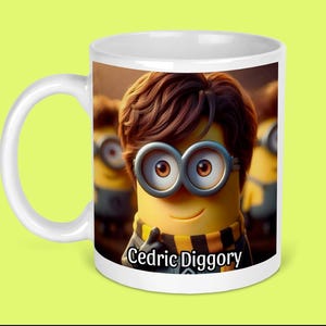 May include: White ceramic mug featuring a cartoon Minion character with brown hair and round glasses. The Minion wears a black and yellow scarf and the text "Cedric Diggory" is printed on the mug.