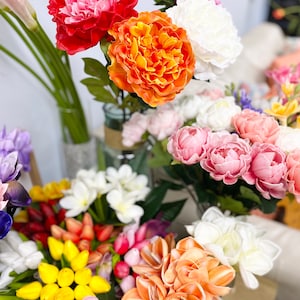 May include: A bouquet of artificial flowers in various colors, including pink, orange, yellow, and white. The flowers are arranged in a vase and include peonies, lilies, and tulips.
