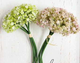 Puede incluir: Dos ramos de flores artificiales con flores blancas. Las flores están atadas con cuerda y tienen tallos verdes.