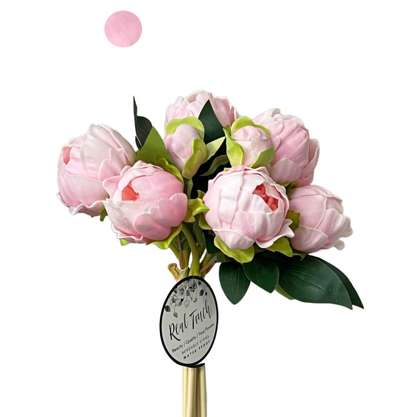 May include: A bouquet of pink artificial peonies with green leaves. The bouquet is arranged in a gold vase and has a tag that reads "Real Touch Beauty / Quality / Real Flowers".