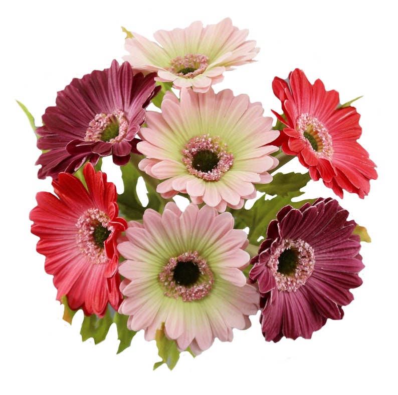 May include: A bouquet of seven artificial gerbera daisies in various shades of pink, red, and purple. The flowers have a realistic appearance and are arranged in a cluster.