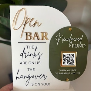 May include: A white and gold open bar sign with the text "Open Bar" and "The drinks are on us! The hangover is on you!" A green oval sign reads "Newlywed Fund" with a QR code and "Thank you for celebrating with us."