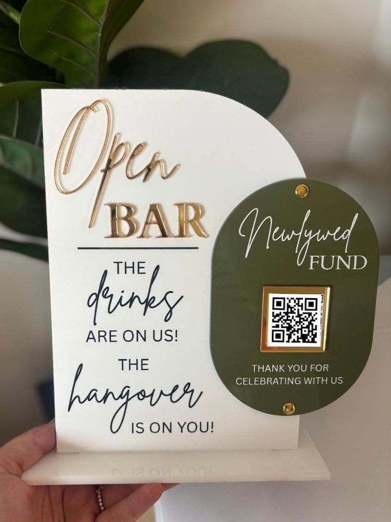 May include: A white and gold open bar sign with the text "Open Bar" and "The drinks are on us! The hangover is on you!" A green oval sign reads "Newlywed Fund" with a QR code and "Thank you for celebrating with us."
