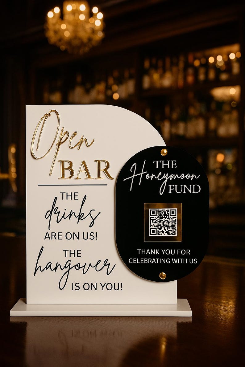 May include: A white and black open bar sign with gold lettering. The sign reads "Open Bar, The drinks are on us! The hangover is on you!" and "The Honeymoon Fund". Includes a QR code.