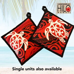 May include: Two red and black square pot holders with a white turtle design. The pot holders have a black border and a loop for hanging. The text "Handmade in Hilo Hawaii" is visible in the upper right corner. The text "Single units also available" is at the bottom.