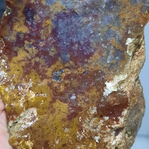 Pu&ograve; includere: Un grande pezzo di agata di forma irregolare con un motivo di colore marrone, arancione e viola. L'agata ha una superficie ruvida e testurizzata.